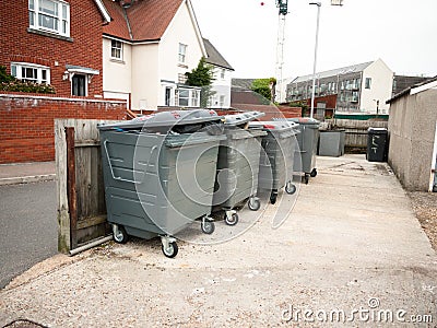 A row of black waste bins outside full Stock Photo