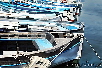 Row of blue fishing boats resting on blue water on sunny day Stock Photo