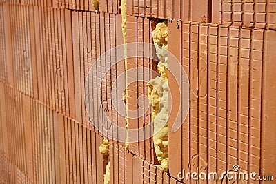 Row of bricks in red and orange color with the inner gap filled with isolating foam on the construction site Stock Photo