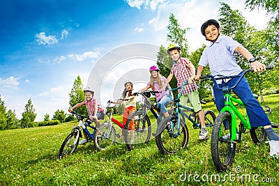 Row of children in colorful helmets holding bikes Stock Photo