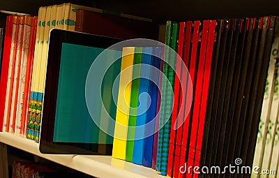 Row of colorful books and electronic book reader Stock Photo