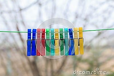 Row of colorful clothespins hanging on a green rope in a gerden Stock Photo