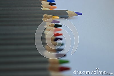 Row of colorful pencils on white table with unfocused foreground. Drawing concept. Isolated crayons. Rainbow of colored pencils. Stock Photo