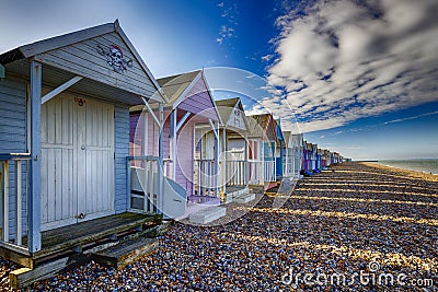 Colourful Beach huts on the shingle beach at hern Bay in Kent Stock Photo