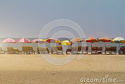 Row of covered wooden deck chairs with colorful umbrellas Stock Photo