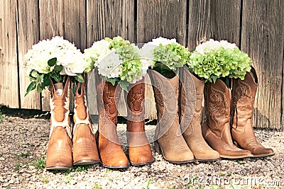 Row of cowboy boots and bouquets at a country theme wedding Stock Photo