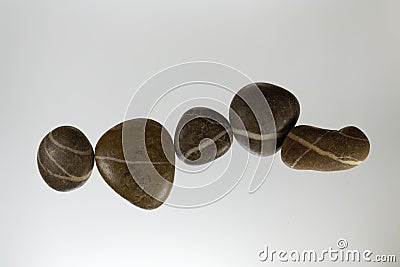 Row of dark pebbles with white veins and a light background Stock Photo