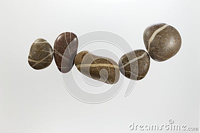 Row of dark pebbles with white veins and a light background Stock Photo