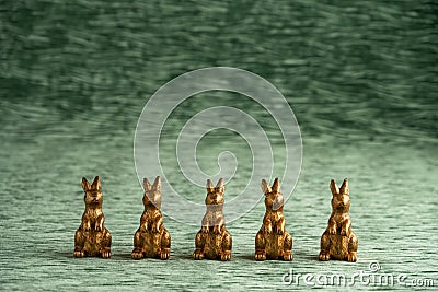 Row of decorative gold bunnies on a textured green velvet background, Happy Easter Stock Photo