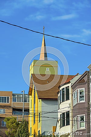 Row of decorative houses in modern city with multiple colors and visible church steeple and cross with power line Stock Photo