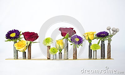 Row of Multicolored Flowers in Old Bullet Casings on White Background Stock Photo