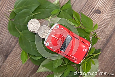 A row of dollar coins surrounded by fresh green leaves and cars climbing on them Stock Photo