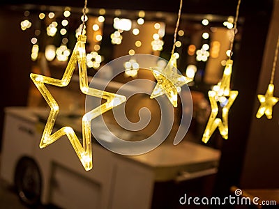 Row of electric lighted stars with warm yellow lights in a against a dark backdrop. Festive / holiday mood concept Stock Photo