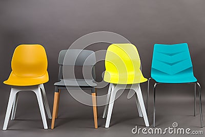 Row of four color plastic chairs isolated on gray background. Furniture series. Stock Photo