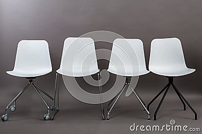 Row of four white plastic chairs isolated on gray background. Furniture series. Stock Photo