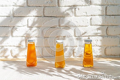 Row of glass bottles of different juices against white brick wall Stock Photo