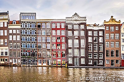 Row of historic Dutch houses along the Damrak canal, dating back to the 18th century, in the historic city center of Amsterdam Editorial Stock Photo