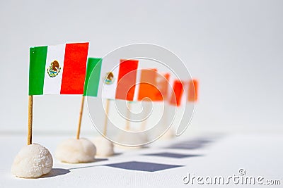 Row of mini Mexican flags in a row with interesting shadows - shallow depth of field with front one in sharp focu against white ba Stock Photo