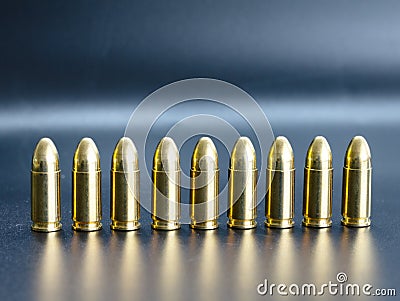 Row of 9 mm pistol bullets on dark background Stock Photo