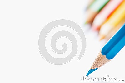 Row of Multicolored Pencils in Background Single Blue Sharp Pencil Pointing with Tip to Blank White Paper. Beginning of Drawing Stock Photo