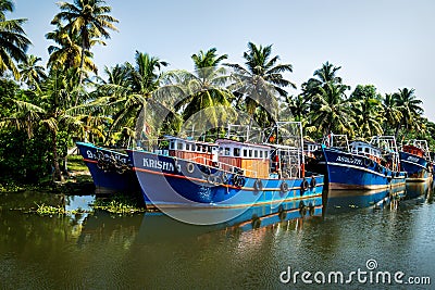 Row of ocean fishing boats from the front along the canal Kerala backwaters shore with palm trees between Alappuzha and Kollam, Editorial Stock Photo
