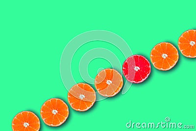 Row of orange cut tangerines with red one. Concept of being unique and creative. Stock Photo