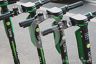 Row of parked electric E scooters , escooter or e-scooter of the company LIME on sidewalk in Berlin Editorial Stock Photo