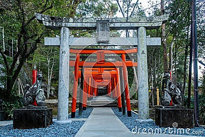 Row of red torii gates with two stone statues of guardian foxes on the sides in Suwa Shinto Shrine in Nagasaki, Japan. Stock Photo