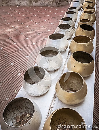 Row of silvery and golden alms bowls in buddhist temple Stock Photo