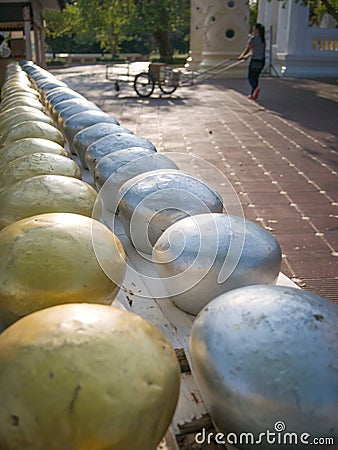 Row of silvery and golden alms bowls in buddhist temple Stock Photo