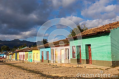 Row of small coloured houses seen in the late afternoon against a grey cloudy sky Stock Photo