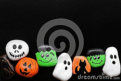 Row of Spooky Cartoon Halloween Painted Rocks Lined up Along Bot Stock Photo
