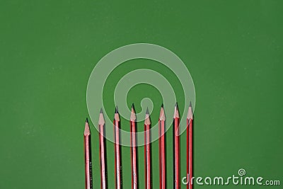 Row of striped pencils of different sharpness on the green background Stock Photo