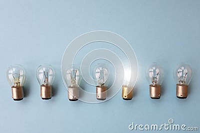 Row of switched off light bulbs with one switched on. Stock Photo