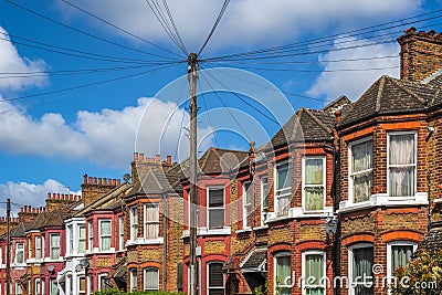 A row of typical British terraced houses in London with overhead cable lines Stock Photo