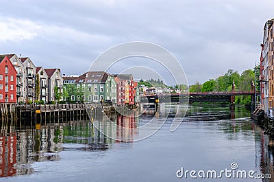 A row of typical colourful Norwegian houses built on pillars on top of a water surface. Stock Photo