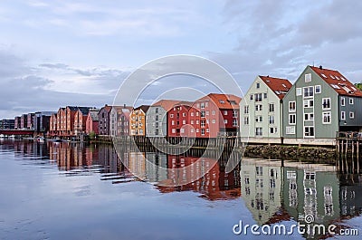 A row of typical colourful Norwegian houses built on pillars on top of a water surface. Stock Photo