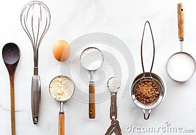 A row of various baking utensils with ingredients on a white marble table. Stock Photo
