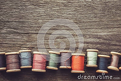 Row of vintage spools of multicolored threads on wooden board. View from above. Copy space for text Stock Photo