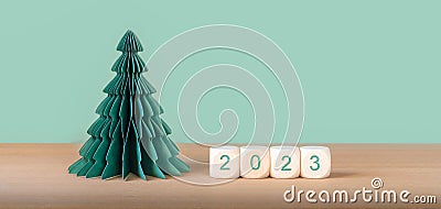 Wooden cubes with year number 2023 near paper Christmas tree decoration. Stock Photo