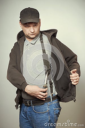 Rowdy bad man in black hooded shirt and black hat armed with dagger Stock Photo