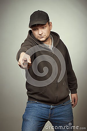 Rowdy bad man in black hooded shirt and black hat posing in studio with dagger Stock Photo