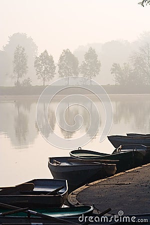 Rowing boats at misty pond Stock Photo