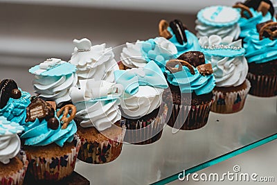 Rows of birthday cupcake with butter white and blue cream icing on a glass stand Stock Photo
