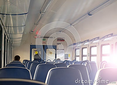 Rows of blue soft seats in a passenger train car. Bright sun shines through the window Editorial Stock Photo