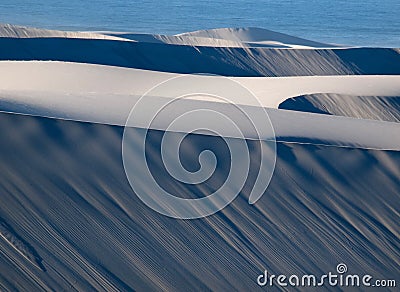 Rows Blue and white Sand duneson the West Coast of Southern Africa with Atlantic Ocean in the background Stock Photo
