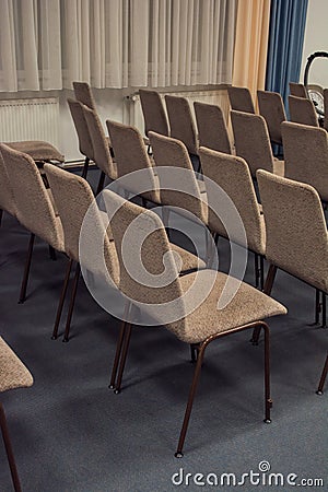 Rows of chairs made of metal and brown velour upholstery are empty in the building Stock Photo