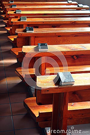 Rows of church benches with bibles. Empty wooden pews. Selective focus Stock Photo