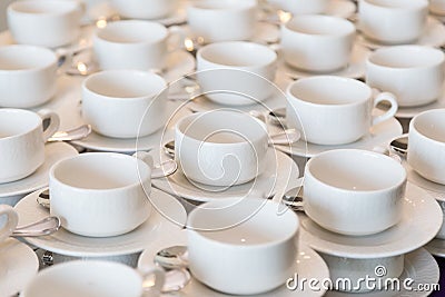 Rows of clean white coffee or tea cups, dish and spoon in a cafeteria or restaurant ready to serve a hot beverage Stock Photo