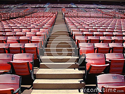 Rows of empty orange stadium seats going upward Stock Photo